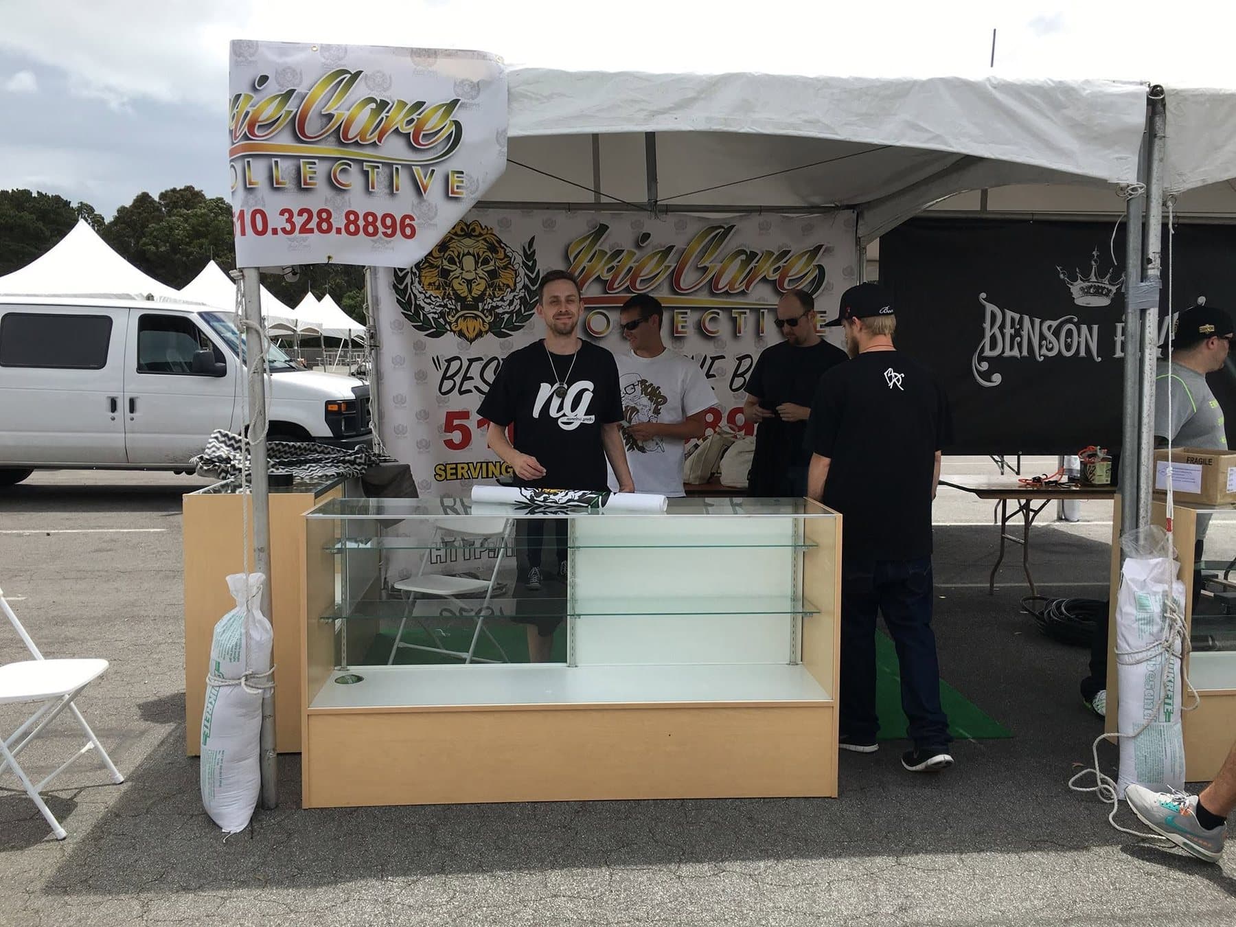 The Irie Care Collective booth at an outdoor cannabis event, with Hirsch behind a glass display counter.