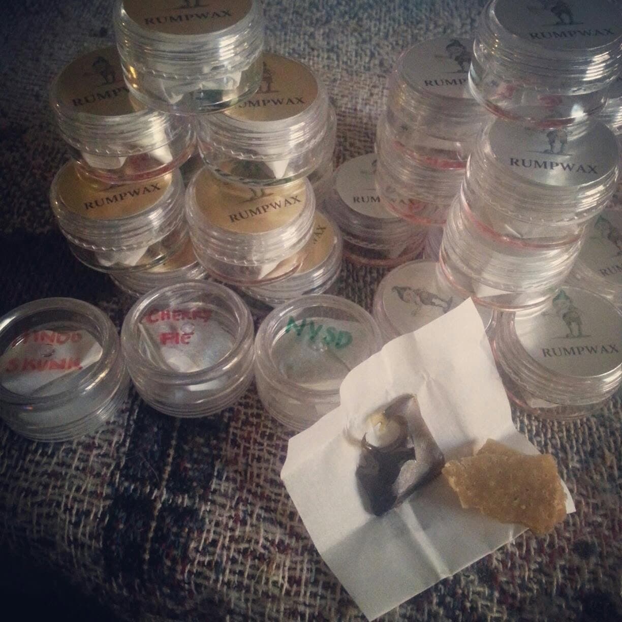 Stacked clear jars labeled Rumpwax, three hand-marked Hindu Skunk, Cherry Pie and NYSD, beside shatter on parchment.